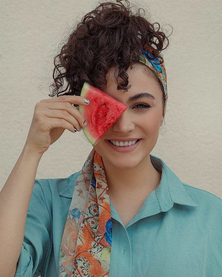 A Woman Covering Her Eye With Watermelon