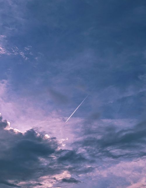 Free A captivating view of a cloudy sky with a distinct contrail, captured during sunset, showcasing nature's beauty. Stock Photo