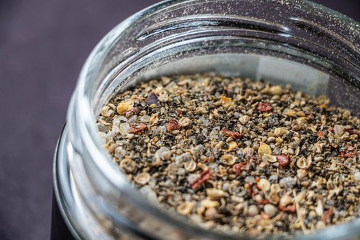 Detailed macro shot of a spice jar filled with assorted ground seasonings and seeds.