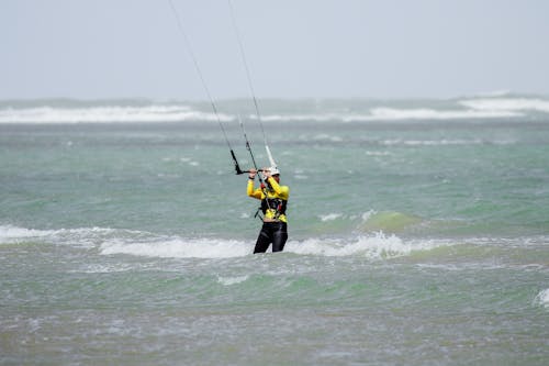 Man in Yellow and Black Wet Suit Trying Kiteboarding