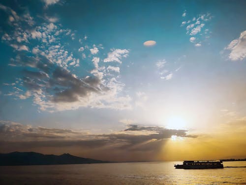 A Boat on Sea Under Blue Sky and White Clouds