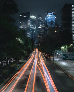 Long exposure of Mexico City's bustling city street with modern skyscrapers at night.