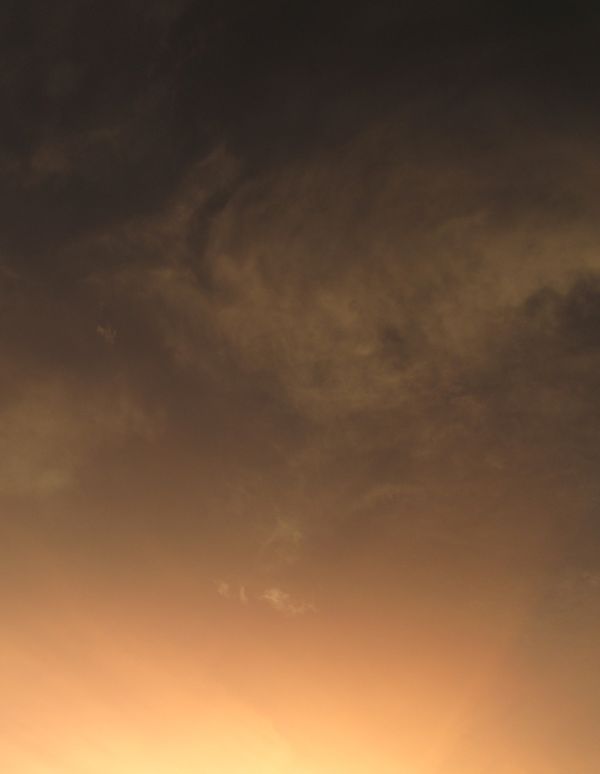 Um céu sereno ao pôr do sol com formações de nuvens dramáticas, lançando matizes quentes pelo horizonte.