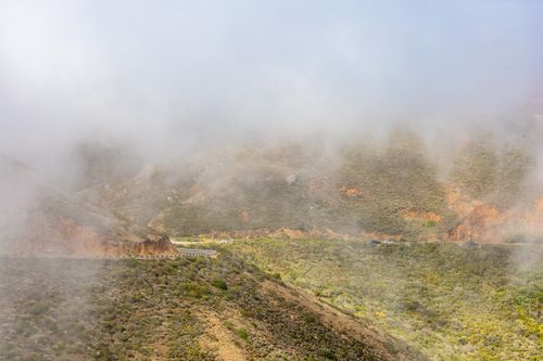 Free A scenic view of a mountain landscape shrouded in mist, revealing a winding road. Stock Photo