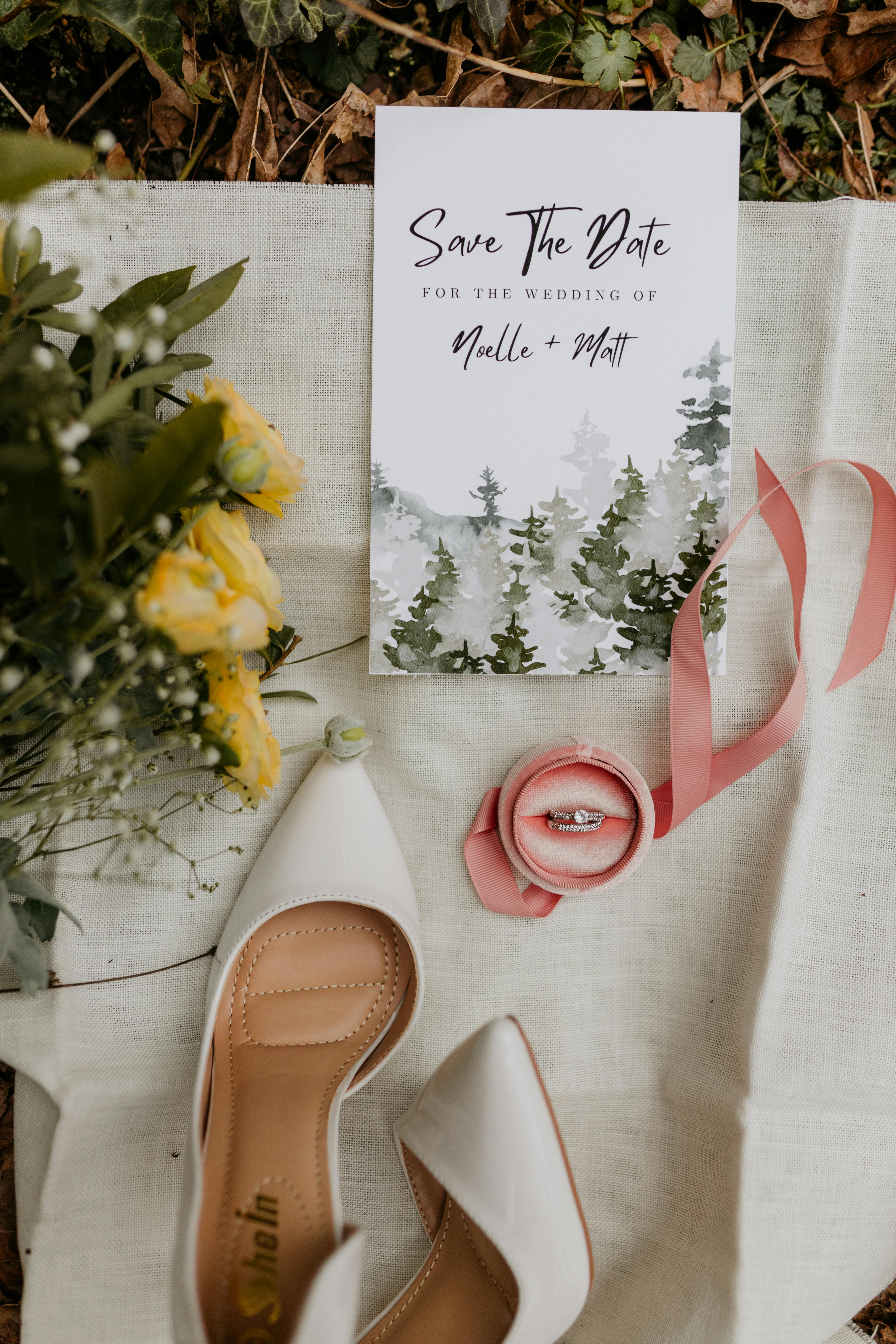 Elegant flat lay of a save-the-date card, yellow flowers, rings, and shoes.