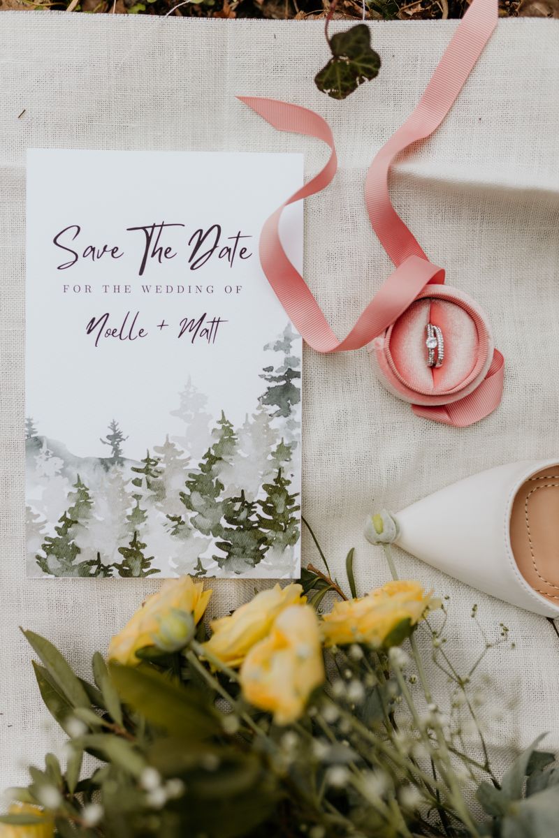 Flat lay of a wedding save the date card with yellow flowers and engagement ring.