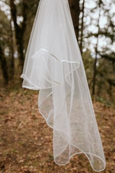 A delicate white sheer fabric elegant drape outdoors in a natural setting.