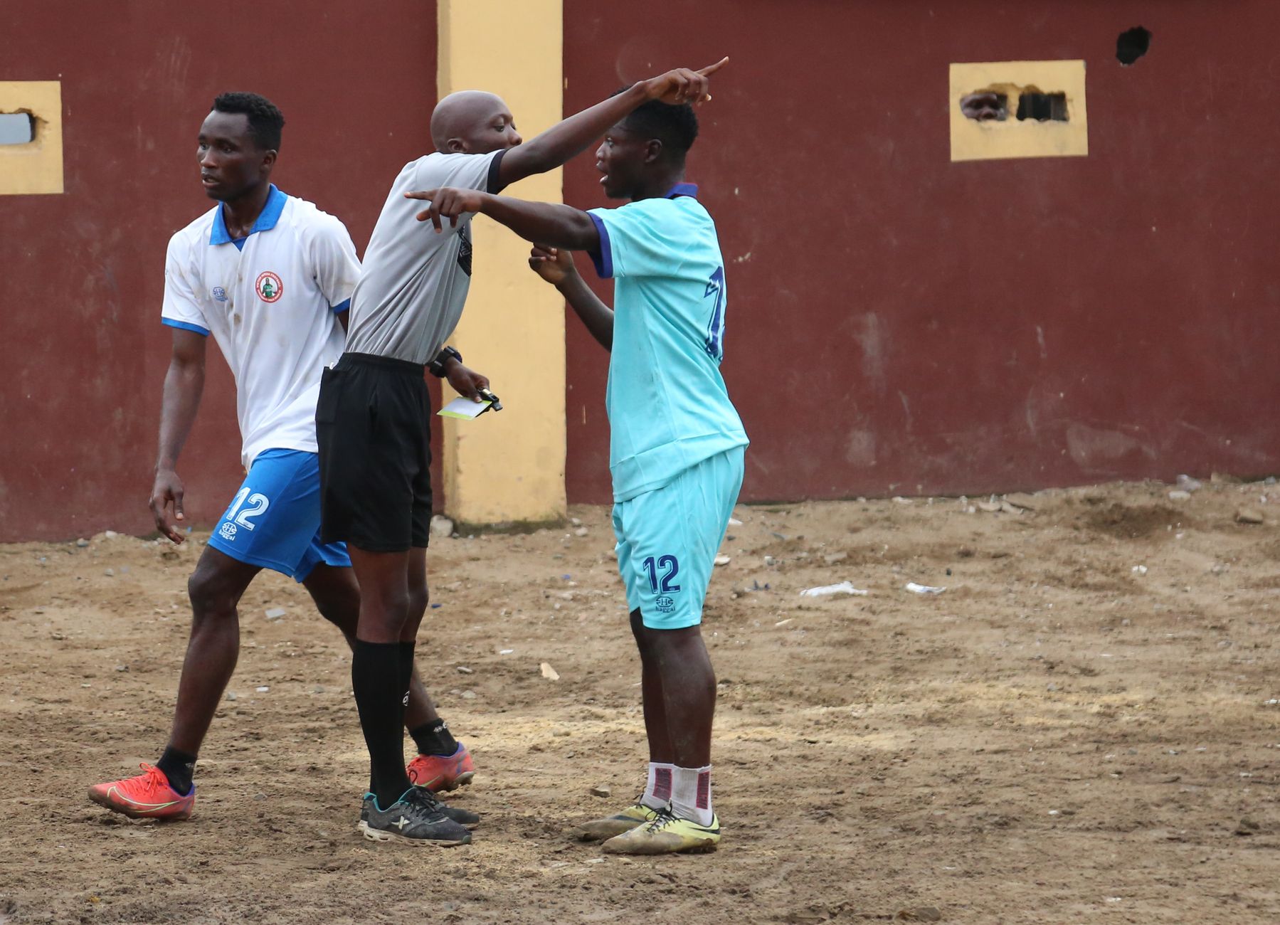 Soccer players and referee in heated discussion during a local match, highlighting sportsmanship.