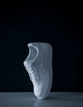 Elevated white sneaker on black background in a studio shoot for fashion and sports.