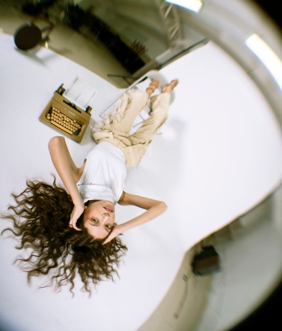 Artistic upside-down portrait of a woman with long wavy hair in a modern studio setting.