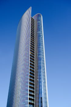 Tall modern skyscraper with reflective glass facade captured against a clear blue sky.