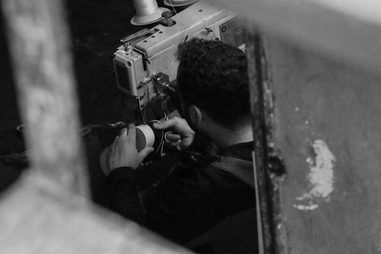 Grayscale Photo Of A Man Fixing A Shoe