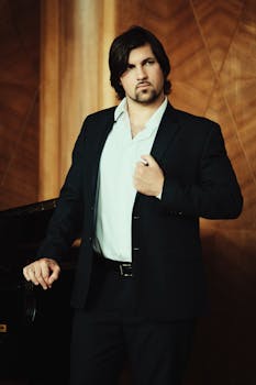 A confident man in a suit posing indoors with a piano.