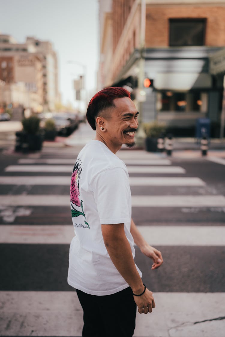 Smiling Asian Man Standing At Pedestrian Crossing In City Street