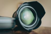Close-up view of a camera lens on a wooden table, perfect for photography and equipment themes.