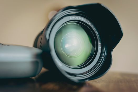 Close-up view of a camera lens on a wooden table, perfect for photography and equipment themes.