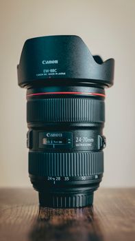 Close-up of a Canon 24-70mm camera lens with hood, highlighting its details.