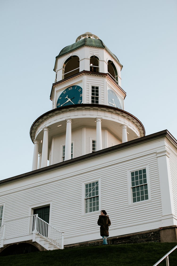 Woman Standing Near White A Wooden Building With Clock Tower