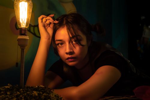 Free Artistic portrait of a woman under warm lighting with a vintage bulb. Stock Photo