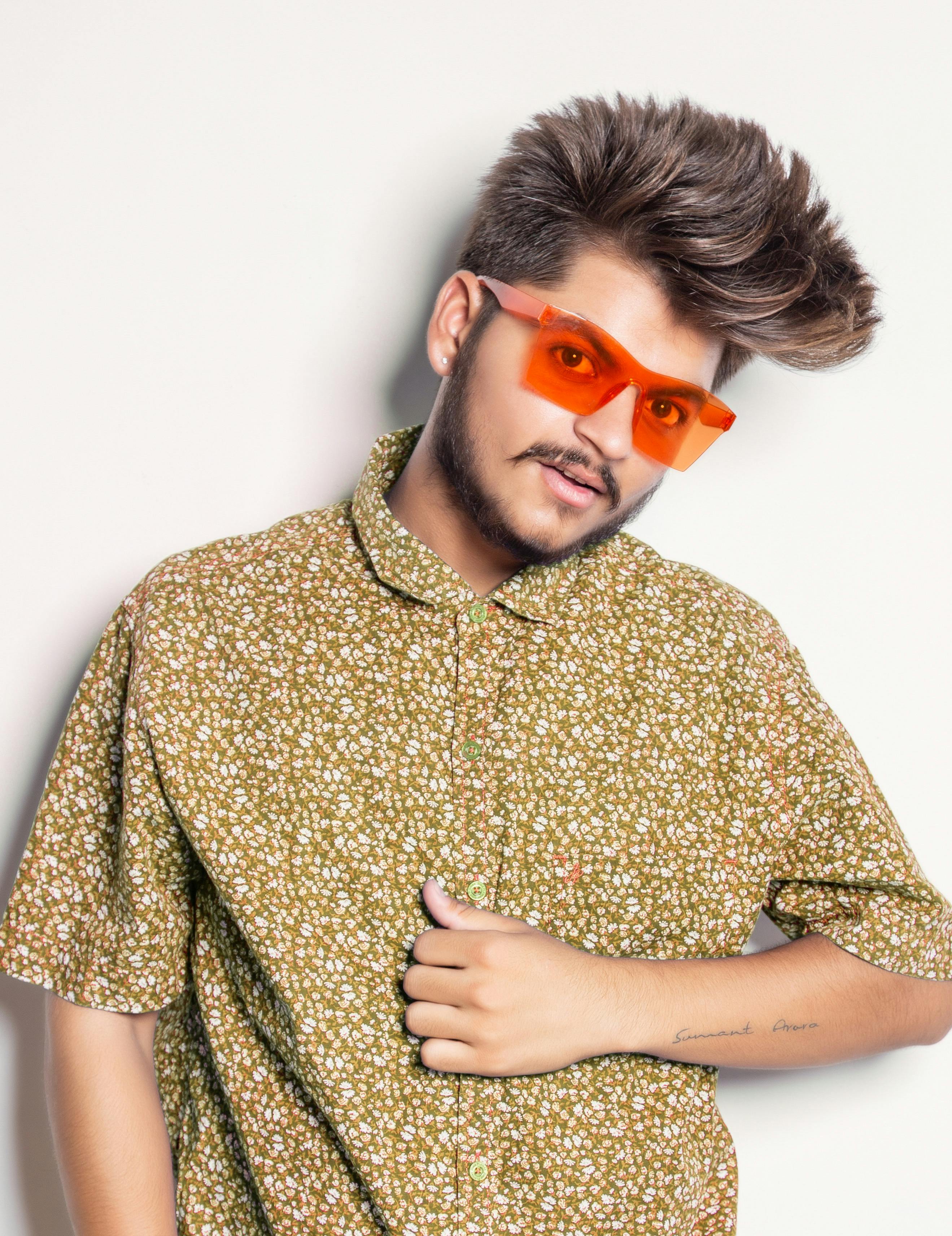 Fashion-forward young man posing with signature eyewear and floral shirt.