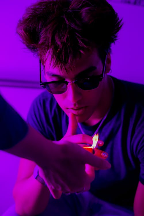 Man in Black Sunglasses Lighting a Cigarette