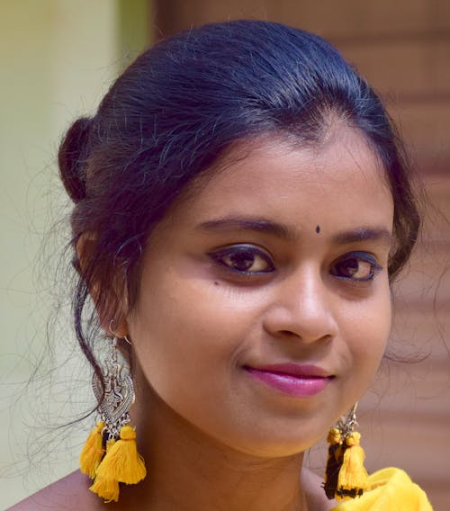 Young Woman Wearing Yellow Earrings Smiling at the Camera