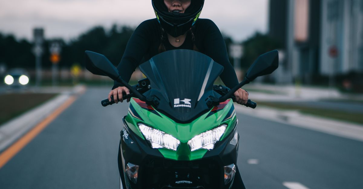 Person Rider A Person Riding on a Green Motorcycle Moving on the Road · Free Stock Photo