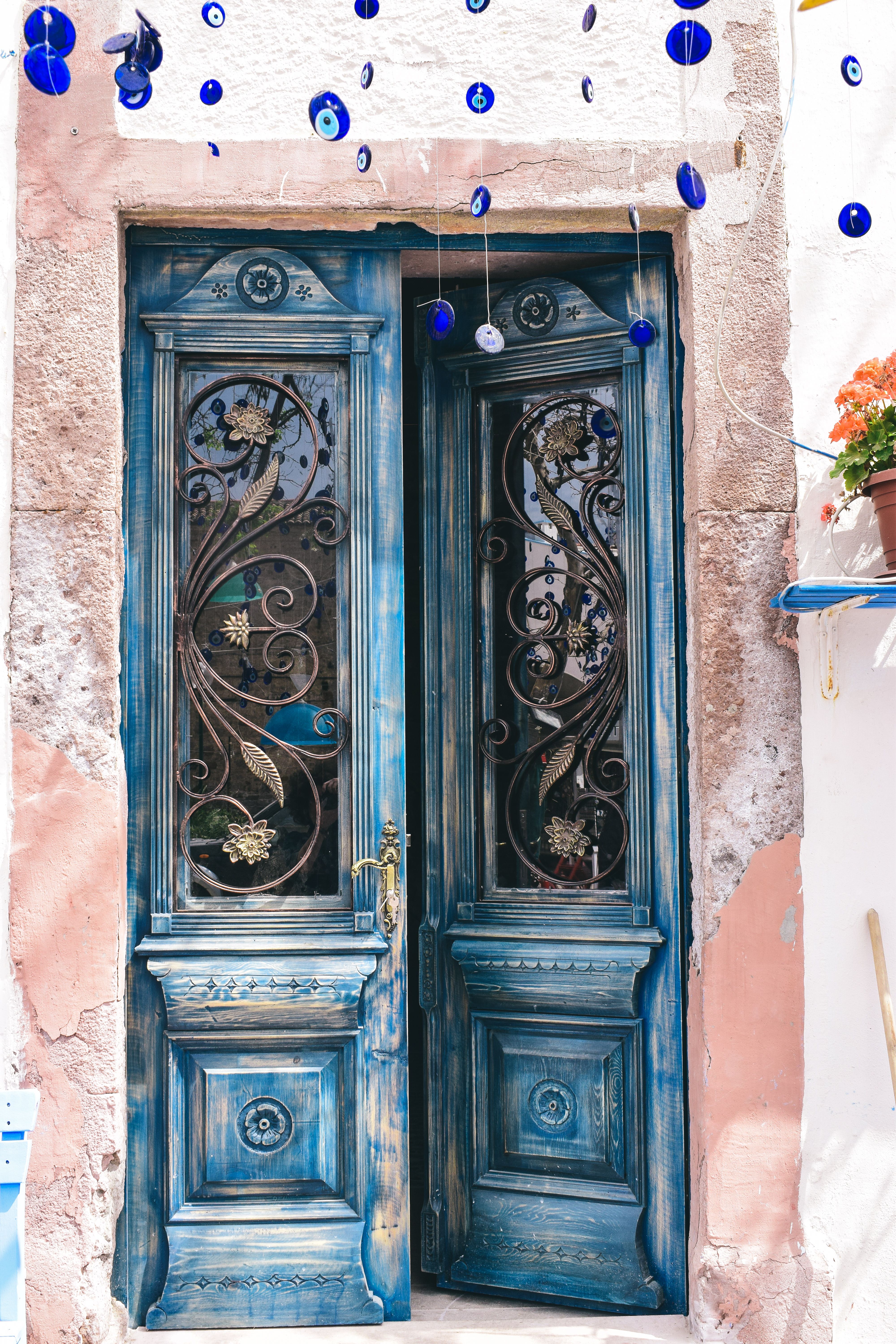 Detailed blue door with intricate design in Türkiye, adorned with hanging evil eyes.