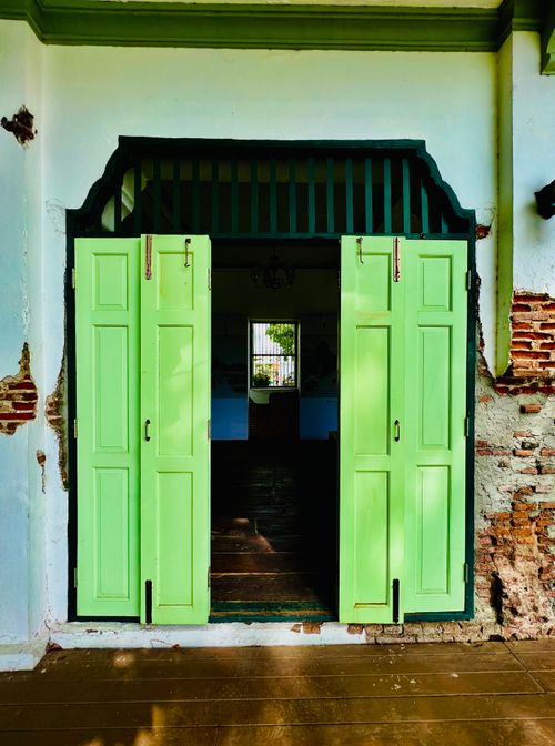 Free Open green wooden doors in an aged brick wall, inviting entrance to a historic building. Stock Photo