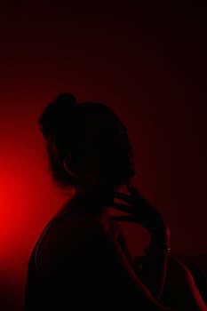 Silhouette portrait of a woman in dramatic red lighting, showcasing a mysterious mood.