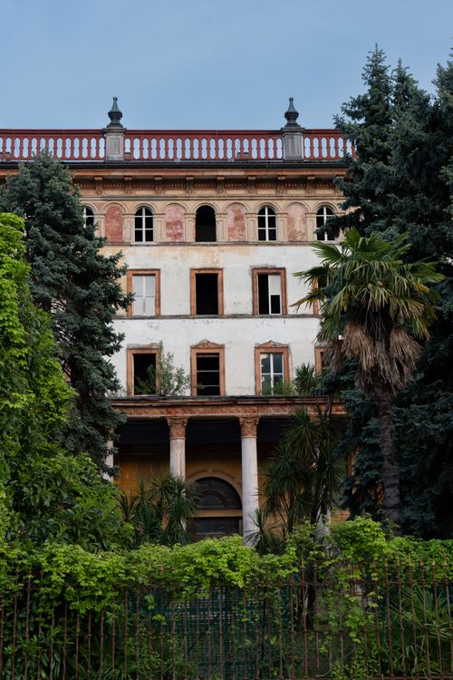 Free A historic abandoned building facade surrounded by lush greenery in Bellagio, Italy. Stock Photo