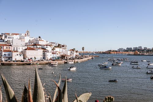 Free Scenic view of boats and colorful buildings along the waterfront in Ferragudo, Portugal. Stock Photo