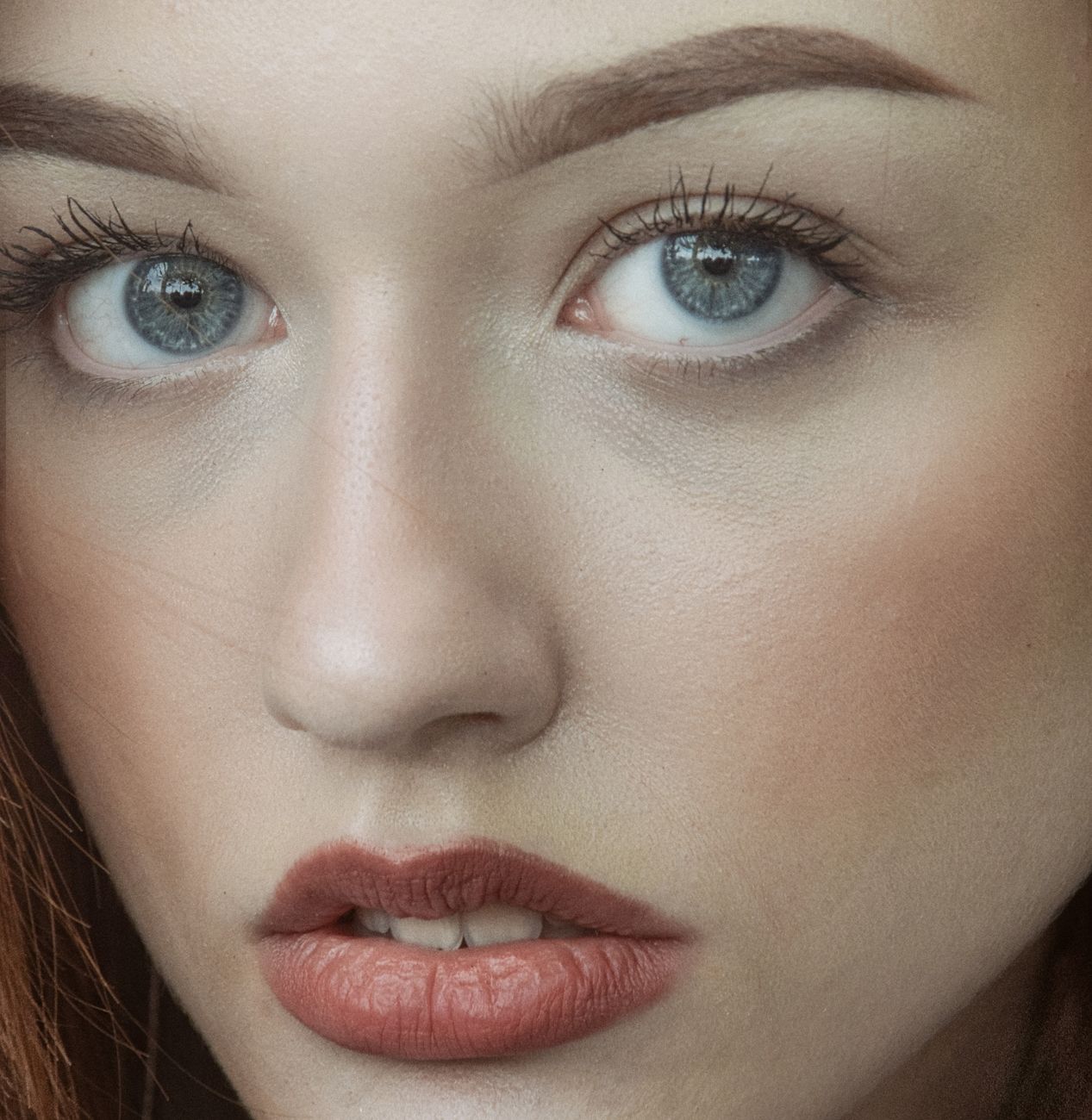Detailed close-up of a woman's face with blue eyes and red lips.