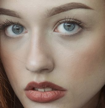 Detailed close-up of a woman's face with blue eyes and red lips.