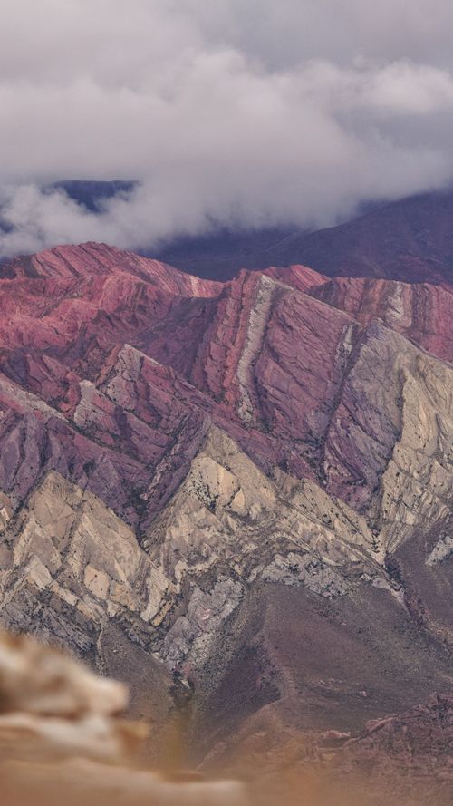 Free A vibrant mountain range with striking colors beneath a cloudy sky. Captured from an aerial perspective. Stock Photo