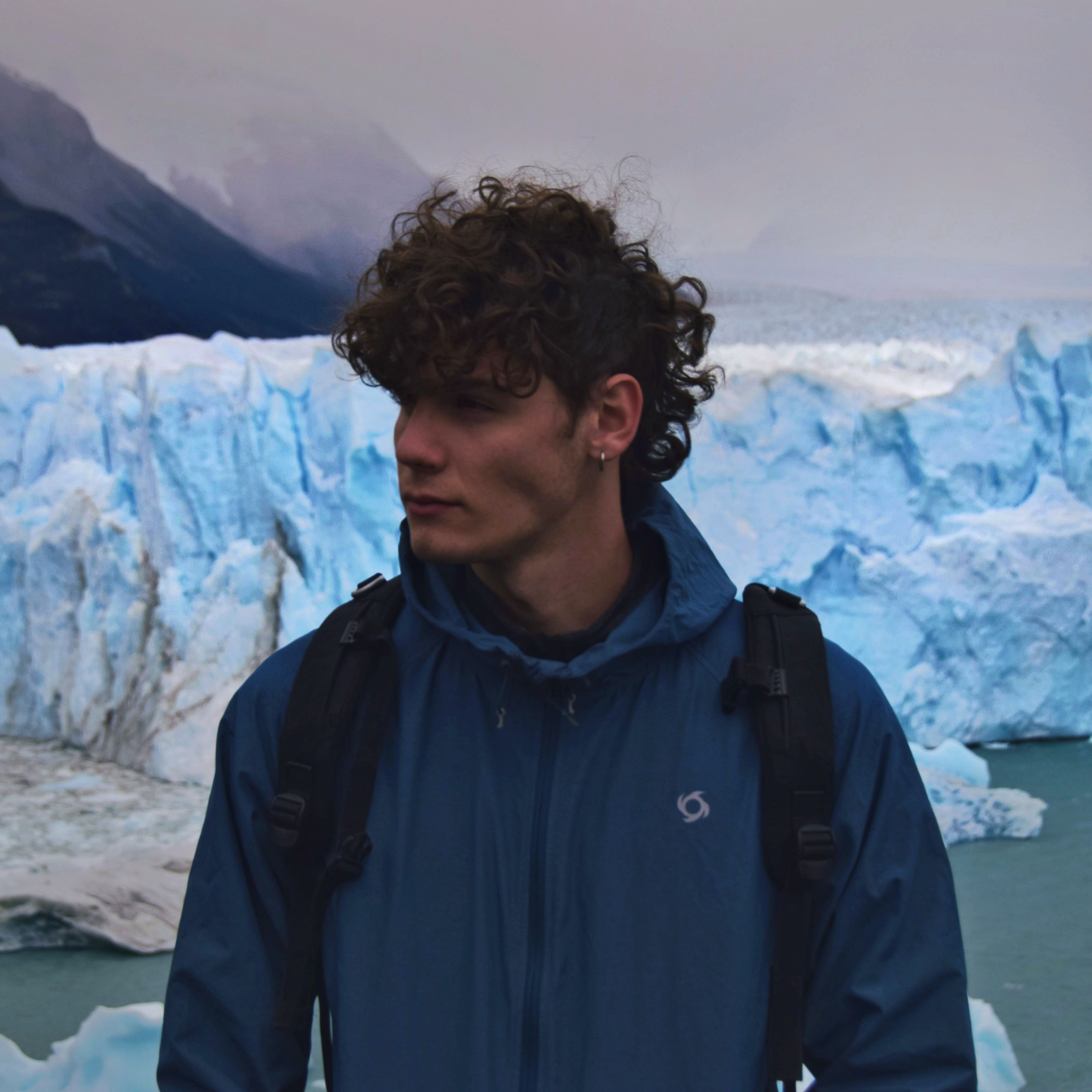 A man stands in front of a stunning glacier, embracing adventure in nature.