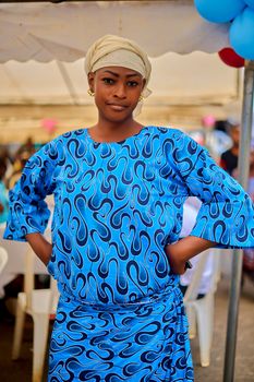 A confident woman in a vibrant blue dress standing outdoors in Abidjan.