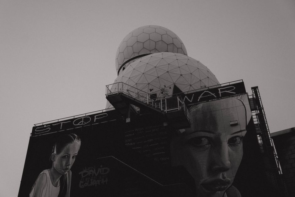 Black and white photo of anti-war mural on Teufelsberg Listening Station in Berlin, emphasizing peace.