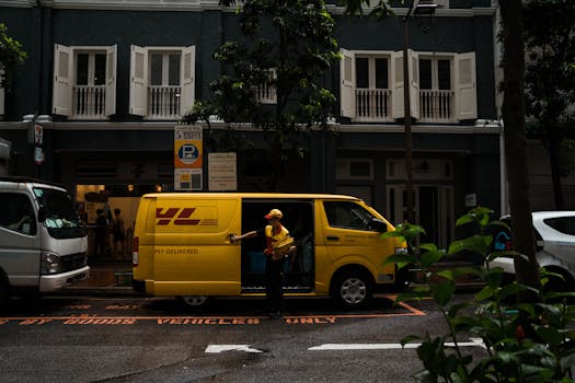 A delivery worker unloading a yellow van in a vibrant Singapore street scene.