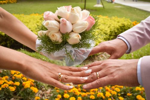 Free Close-up of newlyweds exchanging rings amidst vibrant flowers. Romantic and joyful scene. Stock Photo