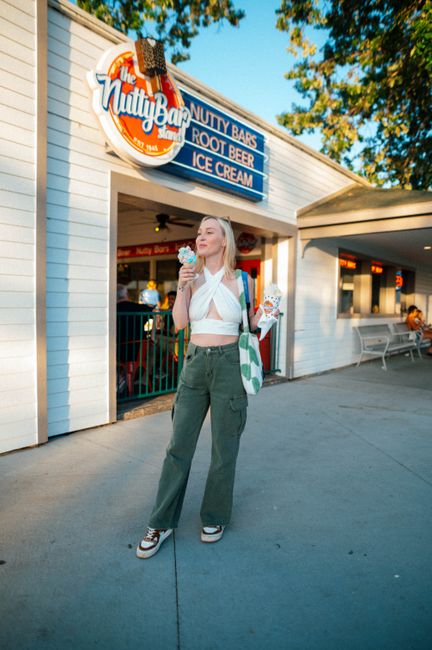 A woman enjoys ice cream outside the iconic Nutty Bar Stand on a sunny day.
