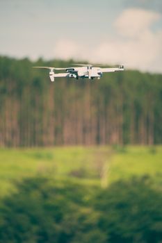 A sleek white drone captures stunning aerial footage over a vibrant forest landscape.