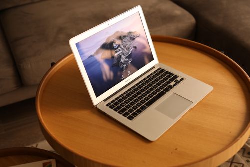 Free Open laptop on a round wooden coffee table in a cozy living room setting. Stock Photo