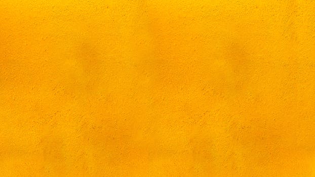 Vibrant yellow textured concrete wall perfect for backgrounds and design projects.