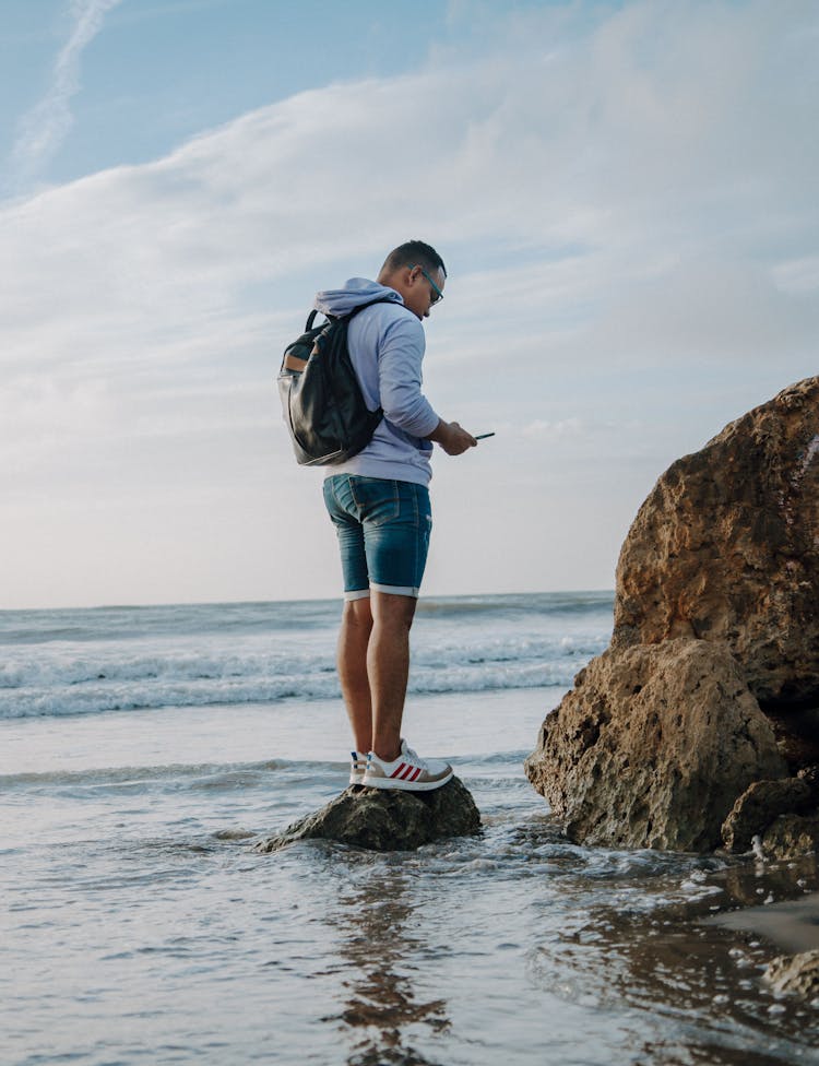 Man Standing On Rock On Beach