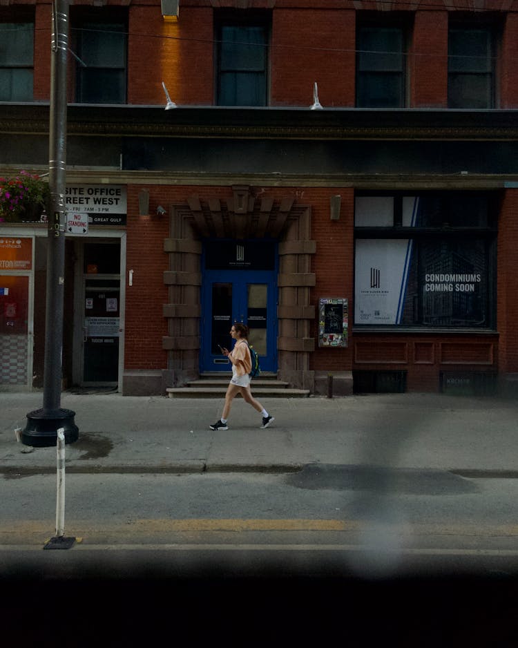 Woman Walking On The Street Near Building