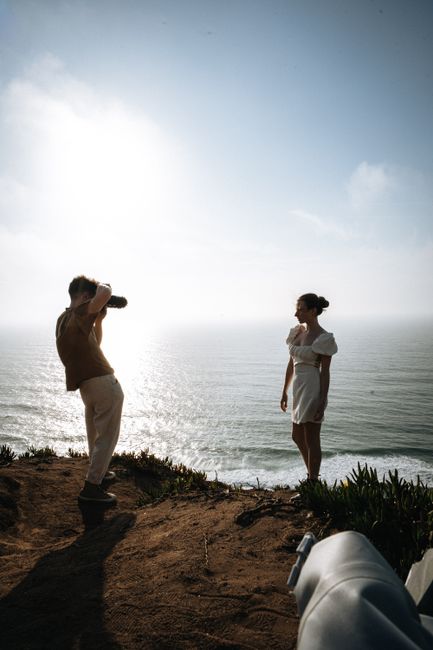 A photographer captures a woman on a scenic Lisbon cliffside with ocean views.