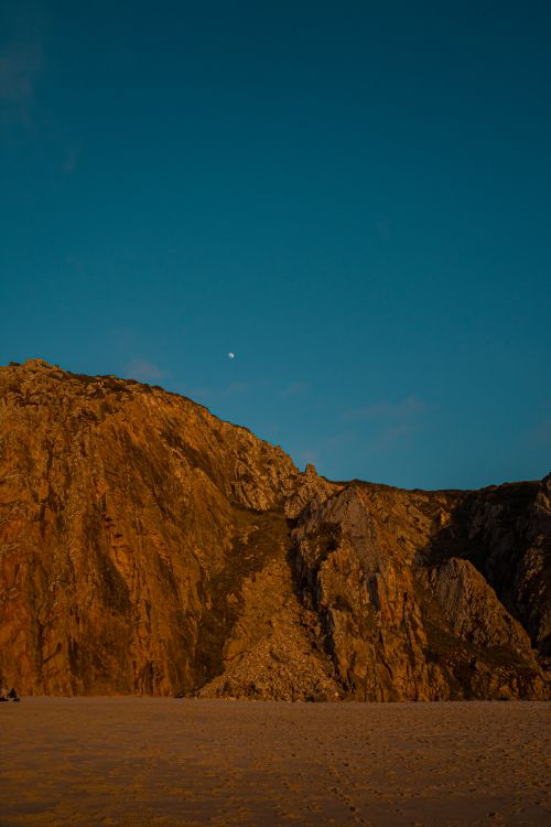 Free Stunning vertical view of a rocky hill against a vibrant blue sky, exuding natural beauty. Stock Photo