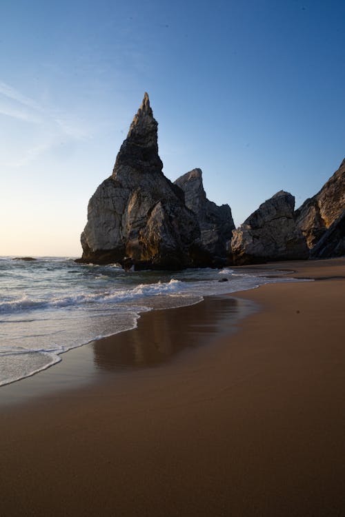 A Rock Formation on the Beach Under the Blue Sky