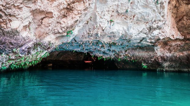 Explore the tranquil beauty of a limestone cave with vibrant, clear water and natural rock formations.